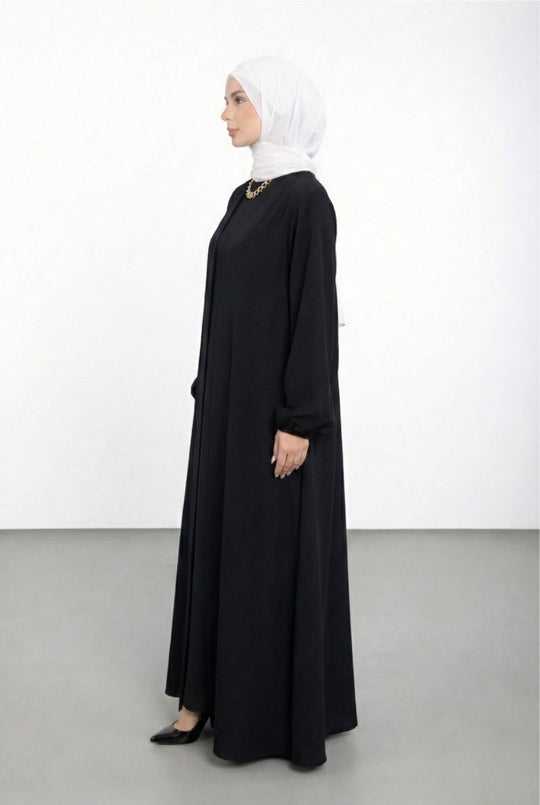 Woman wearing a black abaya and white hijab on a white background