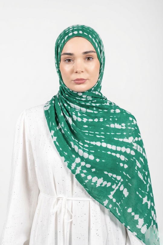 Woman wearing a green and white patterned modal hijab on a white background