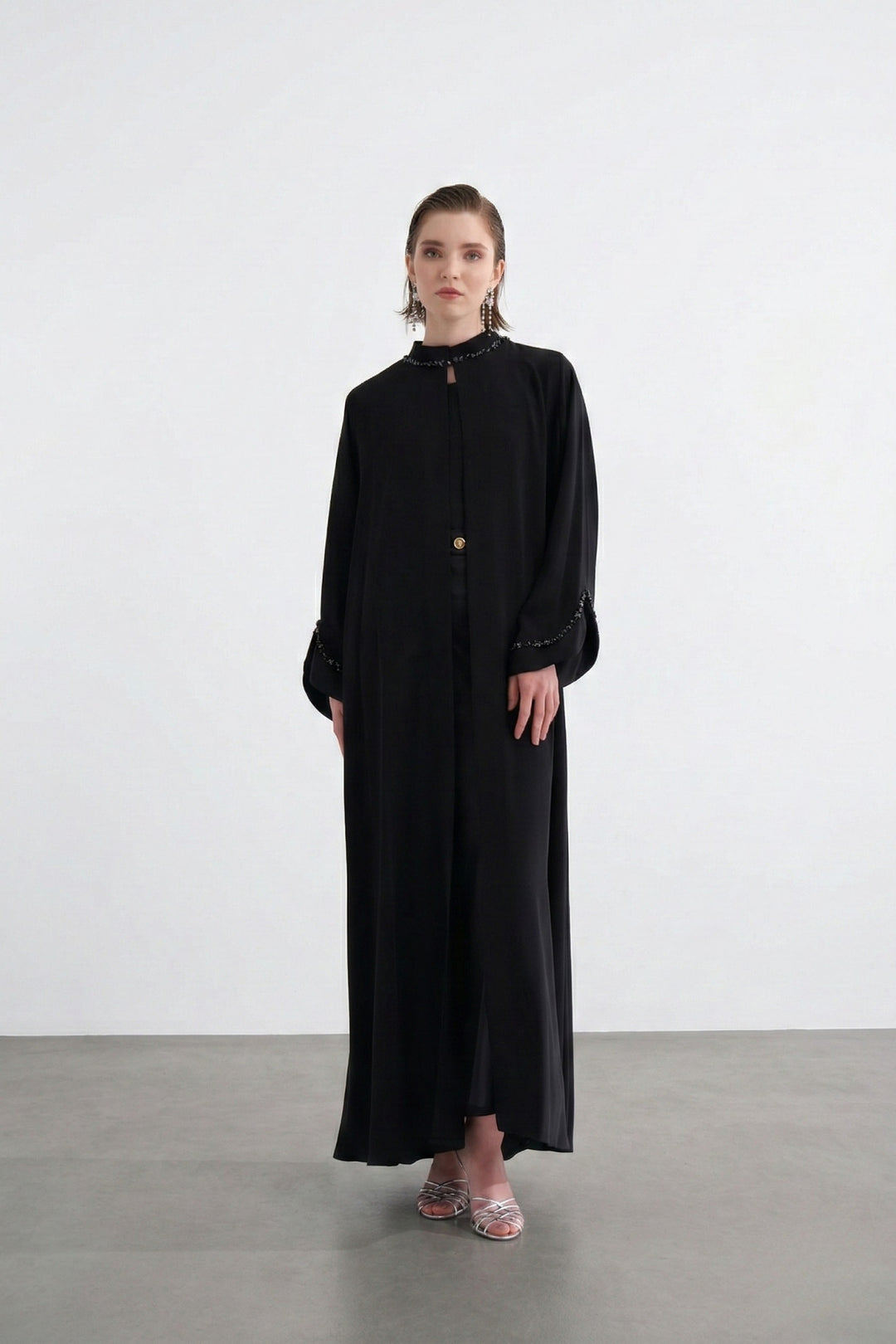 Woman wearing a long black dress against a white background