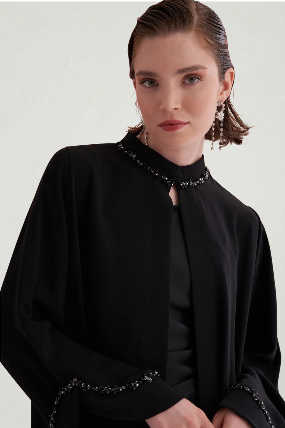 Woman wearing a black outfit with embellishments on a plain background