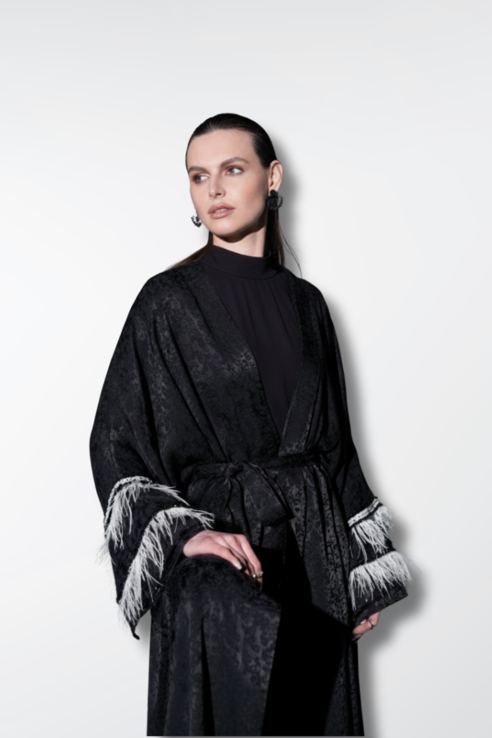Woman wearing a black robe with white cuffs and hem on a white background