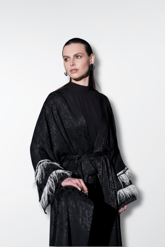 Woman wearing a black robe with white cuffs and hem on a white background