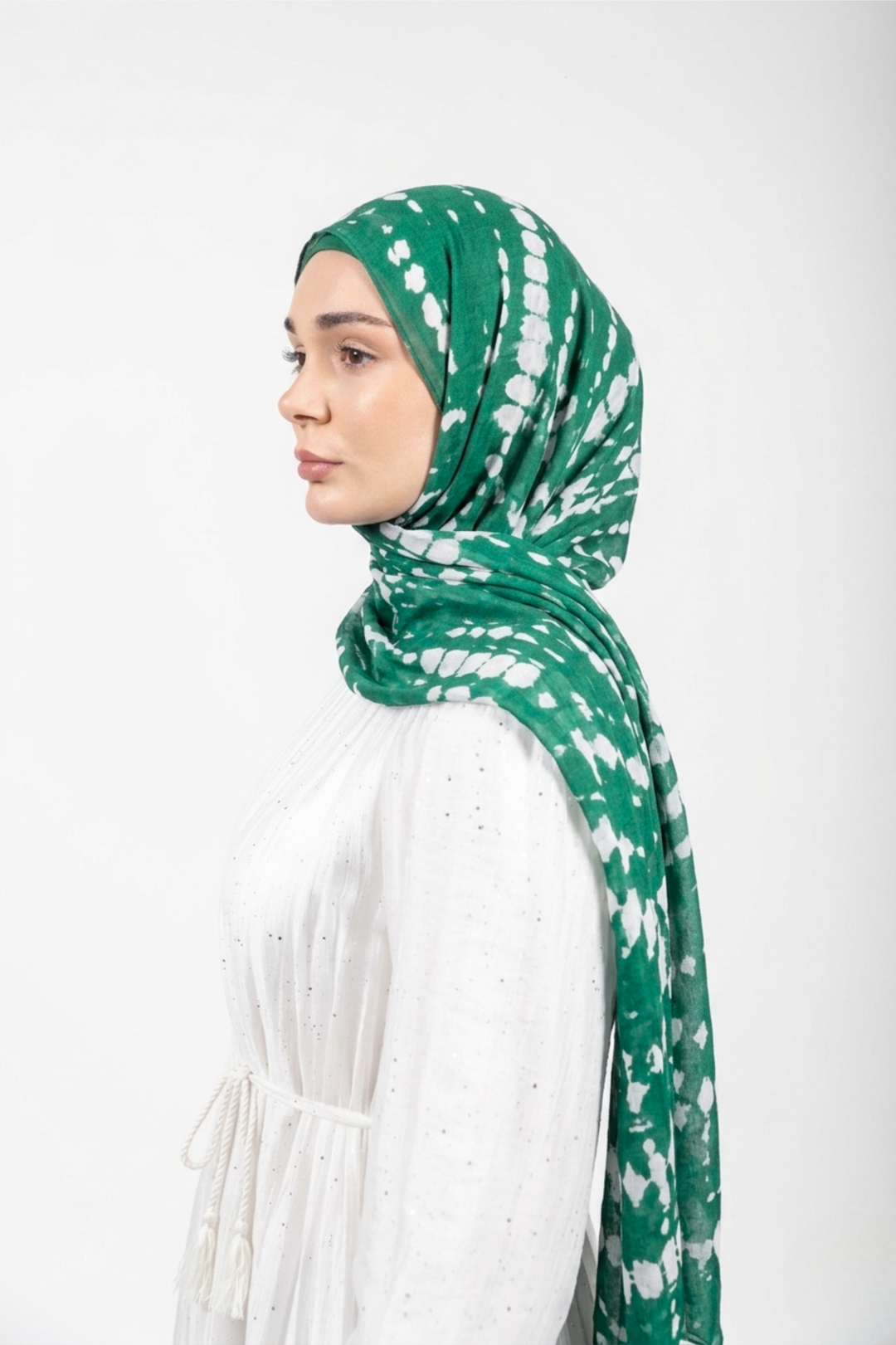 Woman wearing a green and white patterned modal hijab against a white background