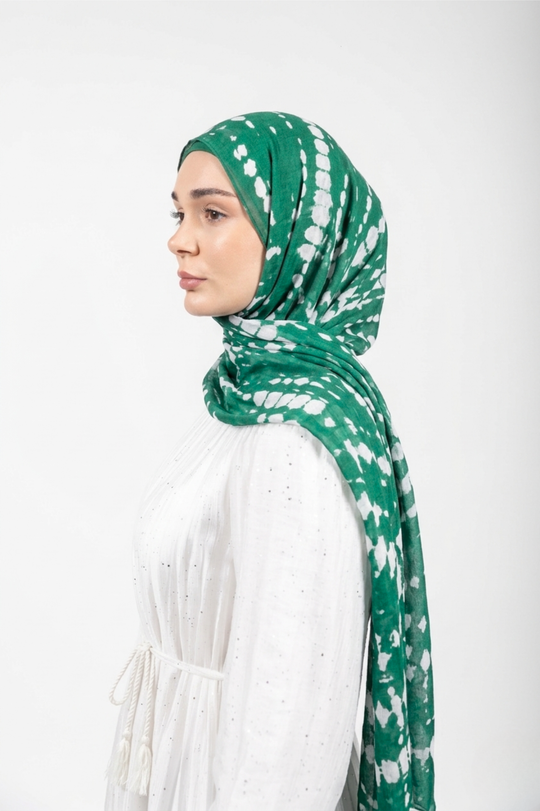 Woman wearing a green and white patterned modal hijab against a white background