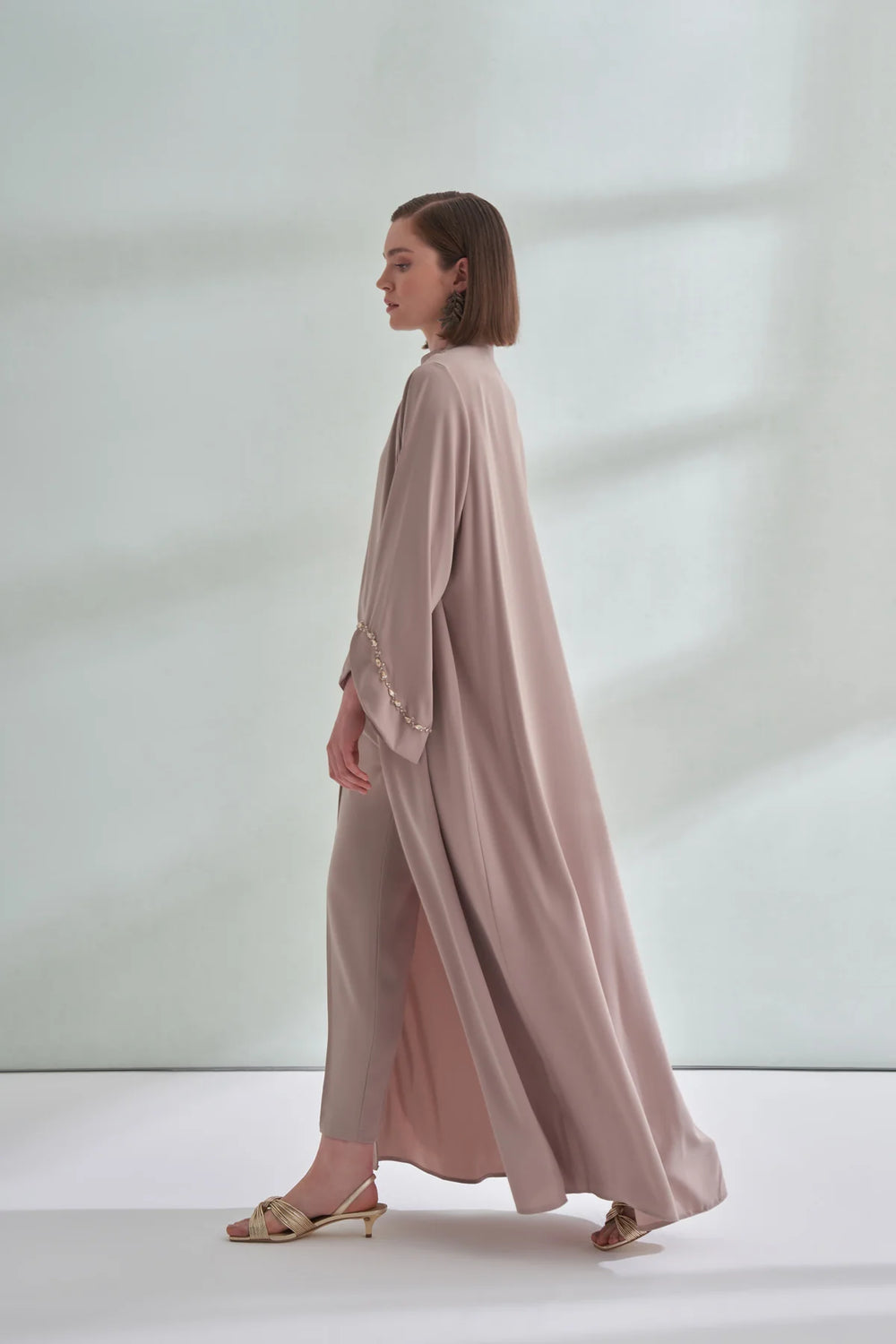 Woman wearing a long, light pink dress with a white background