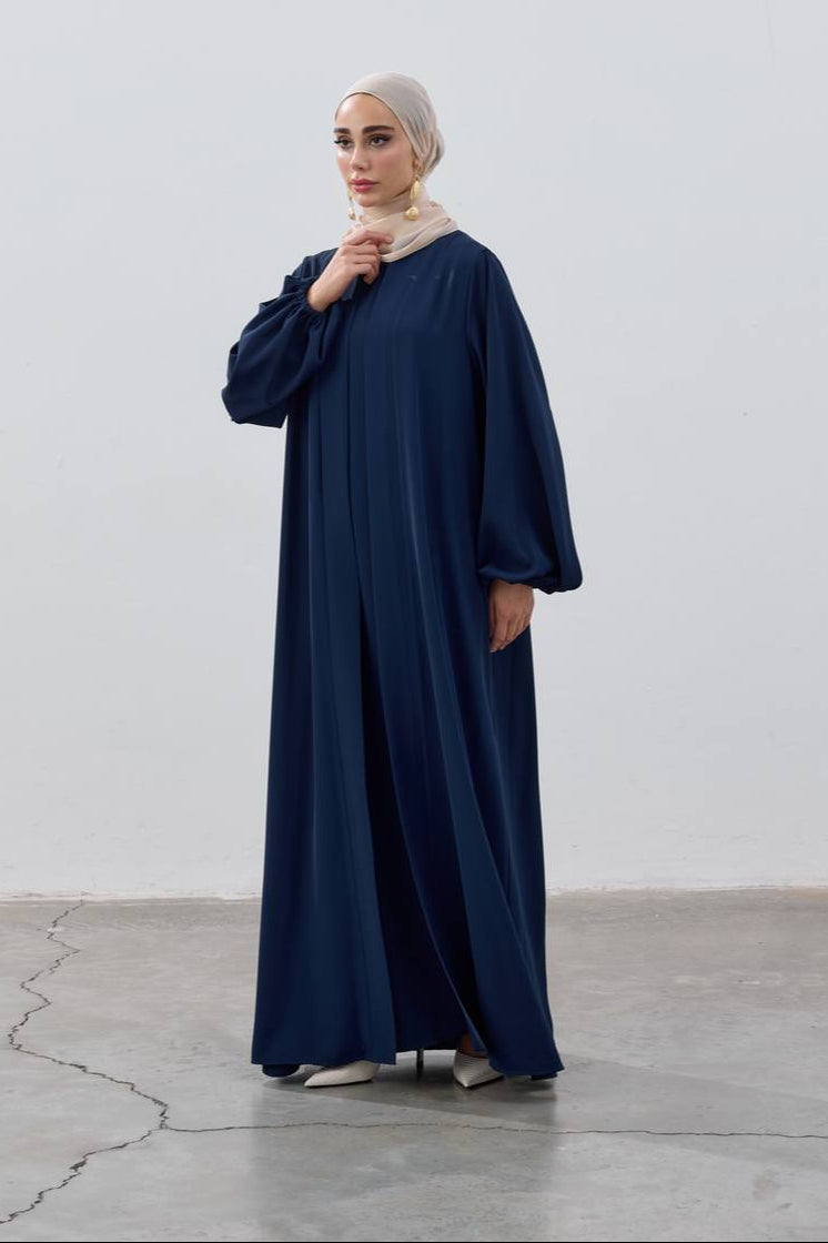 Woman wearing a navy blue abaya against a white background
