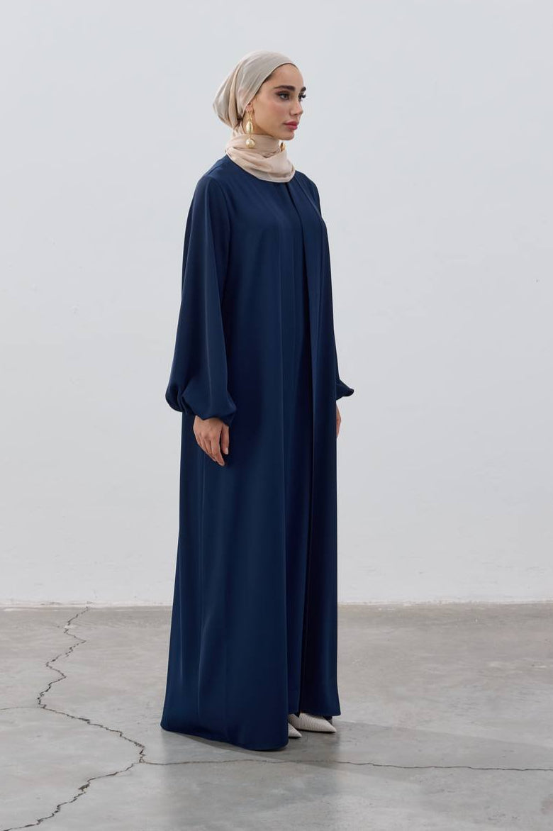 Woman wearing a long navy blue dress against a white background