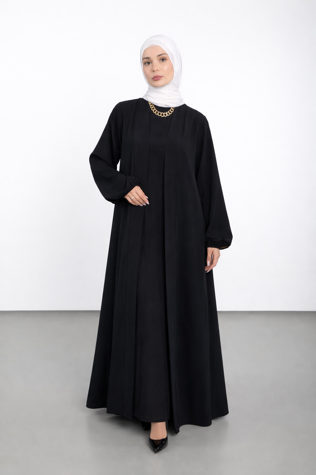 Woman wearing a black abaya and white hijab on a white background