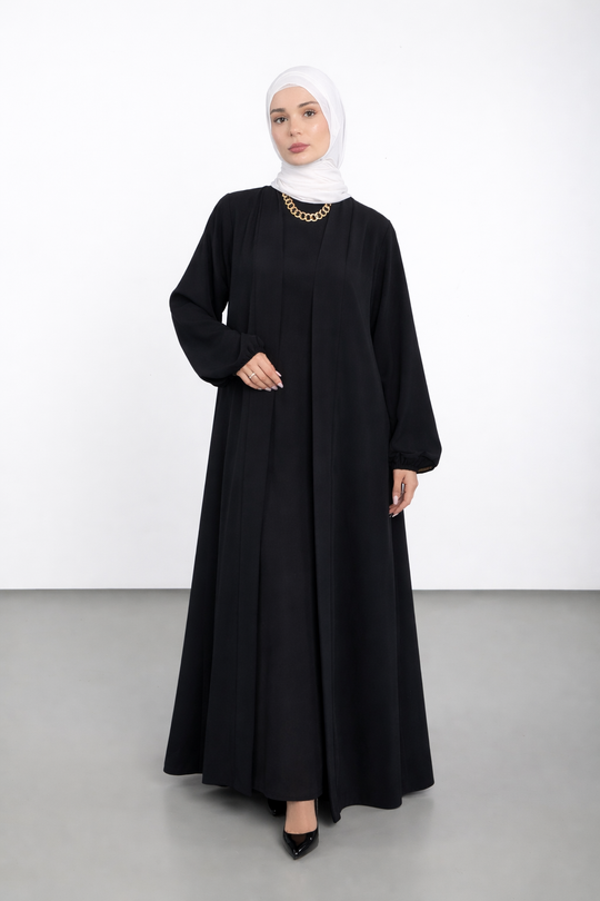 Woman wearing a black abaya and white hijab on a white background