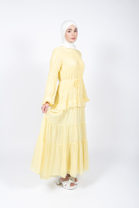 Woman wearing a yellow dress with a white hijab on a white background