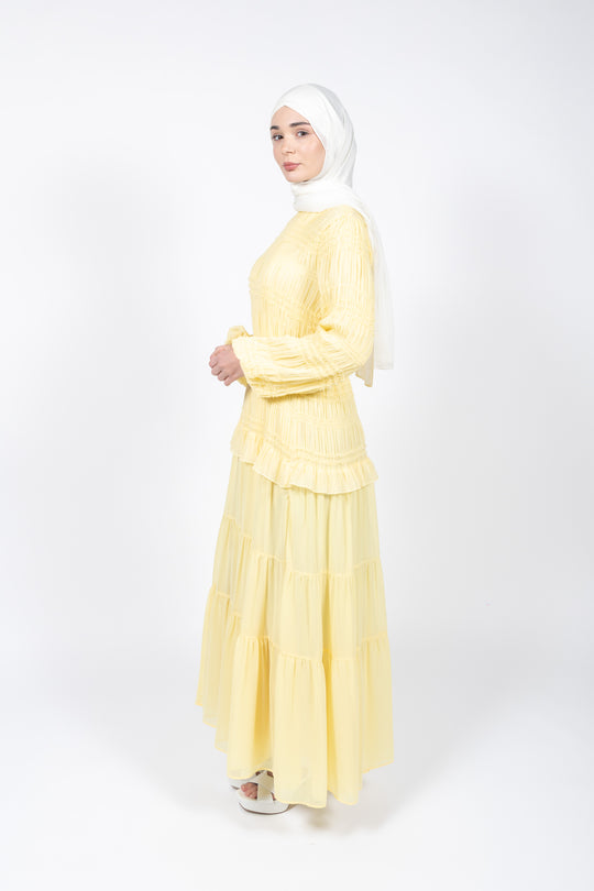 Woman wearing a yellow dress and white hijab on a white background