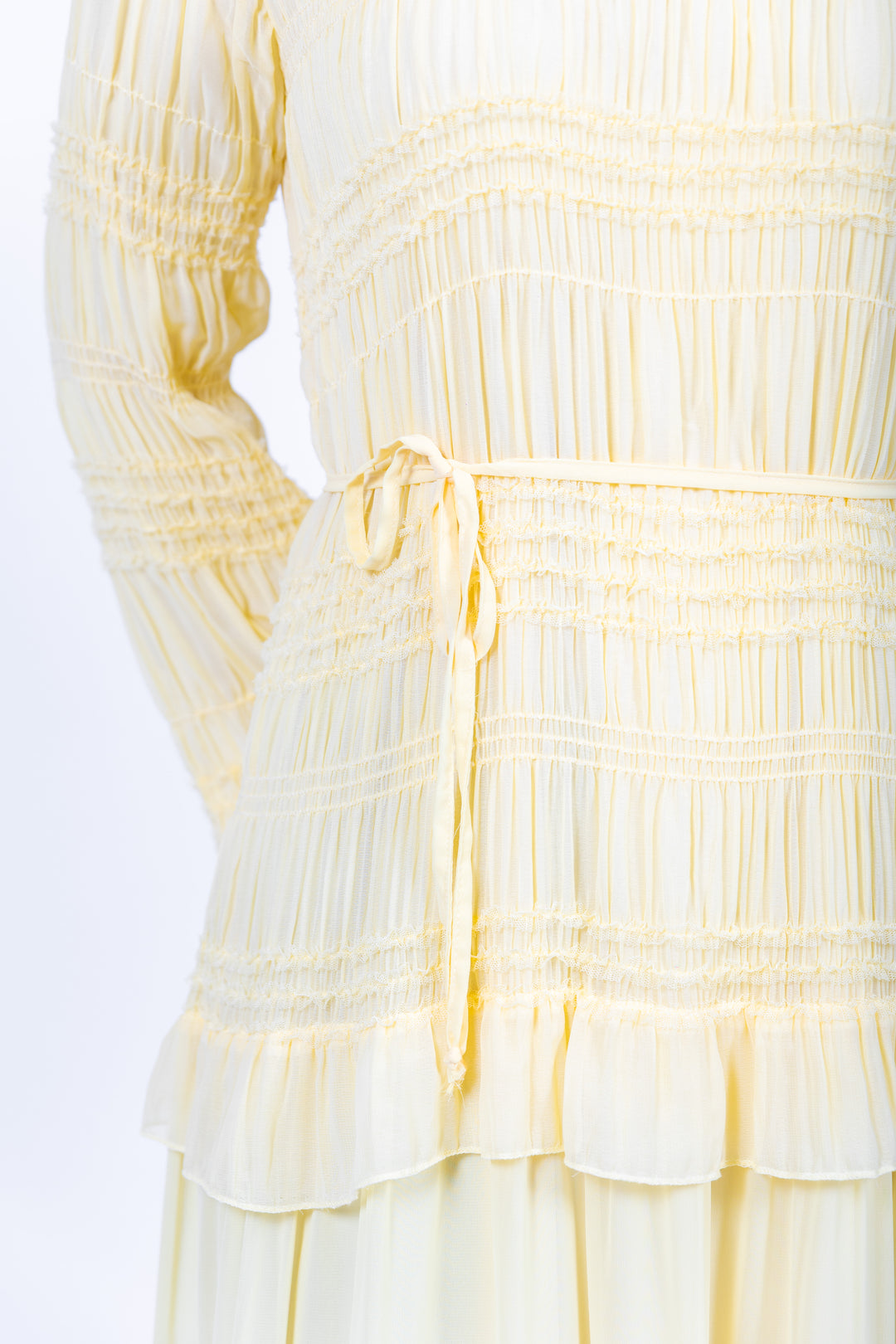 Yellow dress with smocked bodice and ruffled layers on a white background