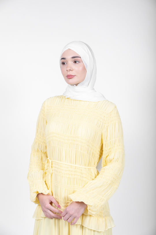 Woman wearing a yellow dress with a white hijab on a white background