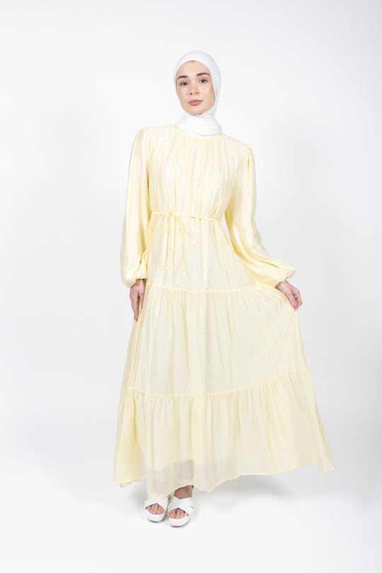 Woman wearing a light yellow dress with long sleeves on a white background