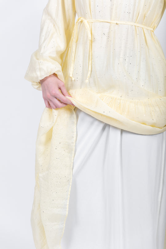 Person wearing a light yellow top with a white background