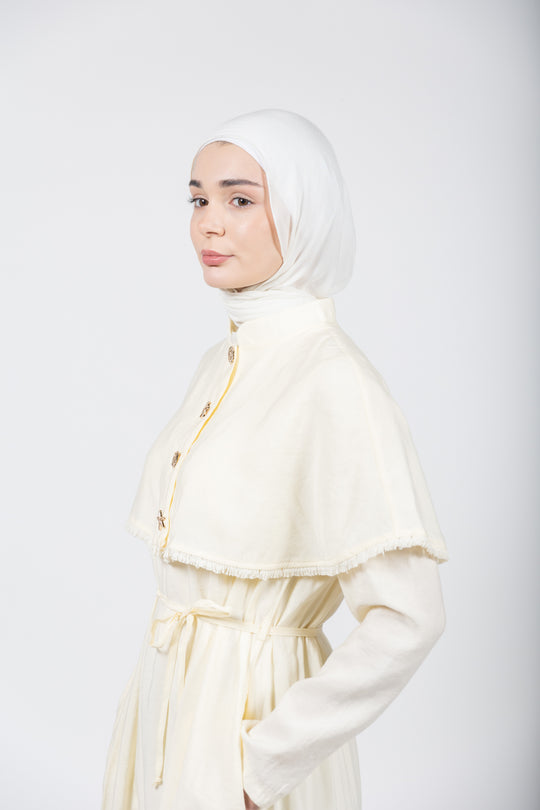 Woman wearing a white outfit with a hijab on a plain background