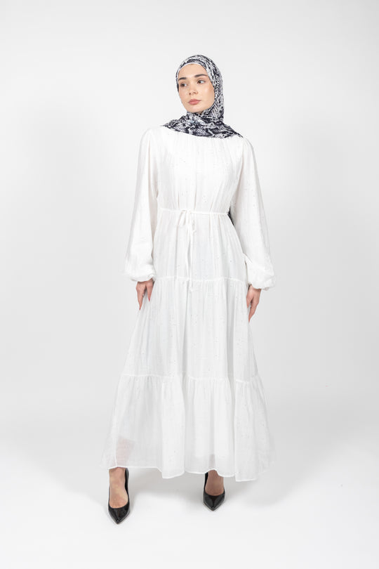 Woman wearing a white dress and patterned hijab on a white background
