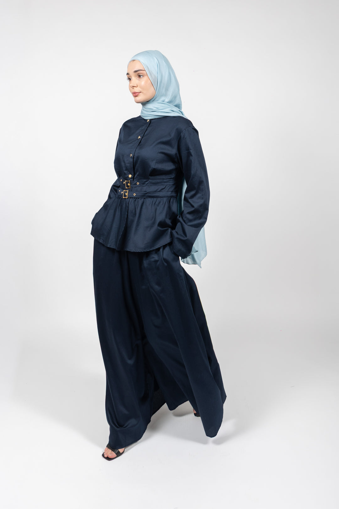 Woman wearing a navy outfit with a light blue hijab on a white background