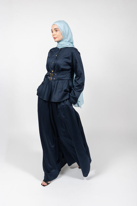 Woman wearing a navy outfit with a light blue hijab on a white background
