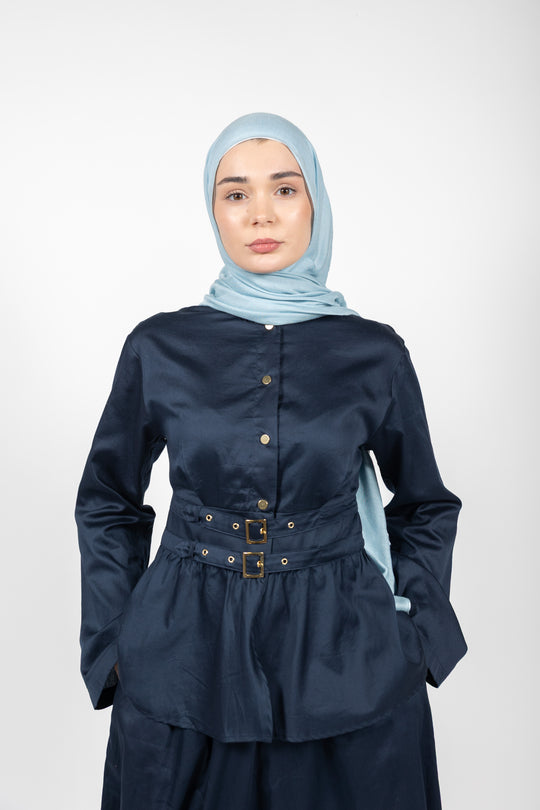 Woman wearing a navy blue outfit with a light blue hijab on a white background