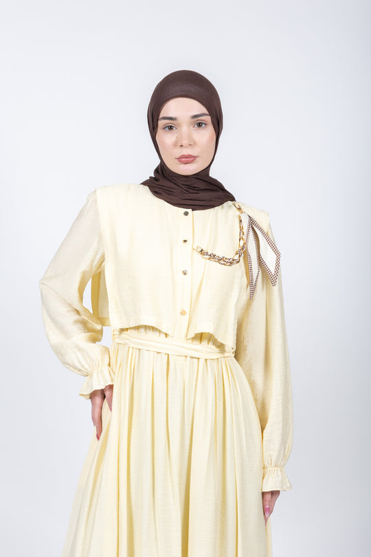 Woman wearing a light yellow dress with a brown hijab on a white background