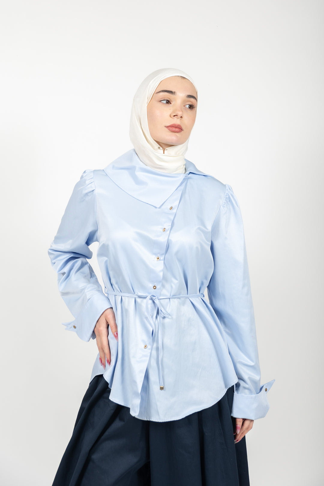 Woman wearing a light blue shirt and hijab on a white background