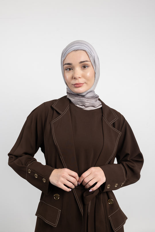 Woman wearing a brown coat and gray hijab on a white background