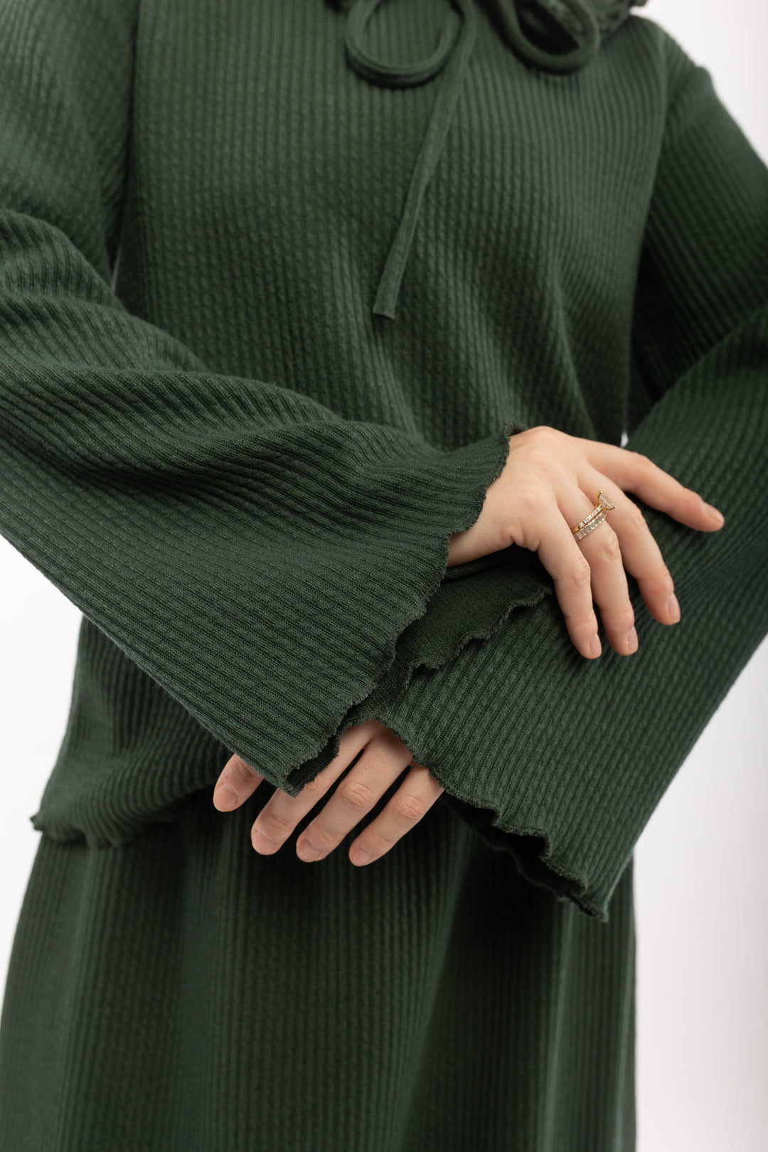 Green ribbed sweater with ruffled cuffs on a white background