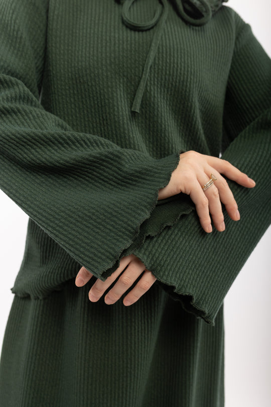 Green ribbed sweater with ruffled cuffs on a white background