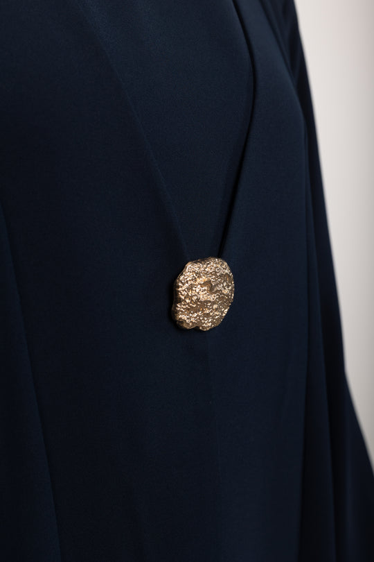 Navy blue blazer with a gold button on a white background