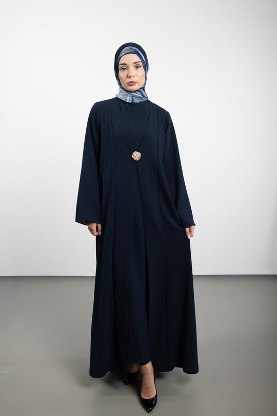 Woman wearing a long dark blue dress with a matching hijab on a white background