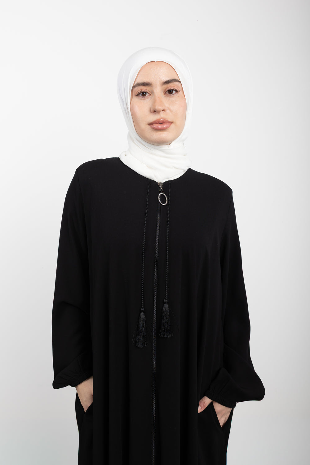 Woman wearing a black abaya and white hijab on a white background