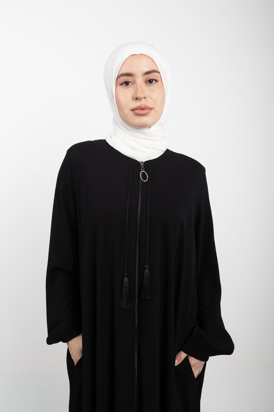 Woman wearing a black abaya and white hijab on a white background