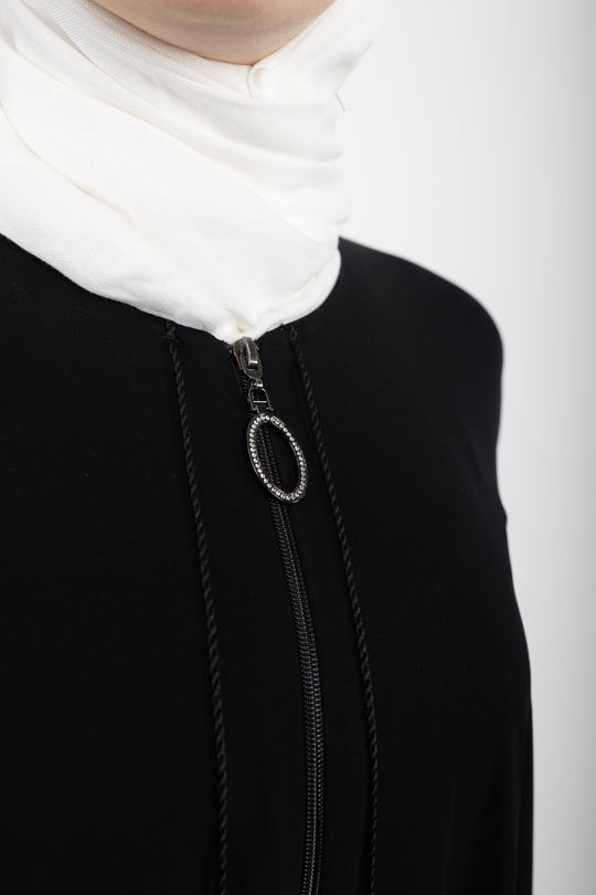 Close-up of a black garment with a zipper and white fabric at the neckline.