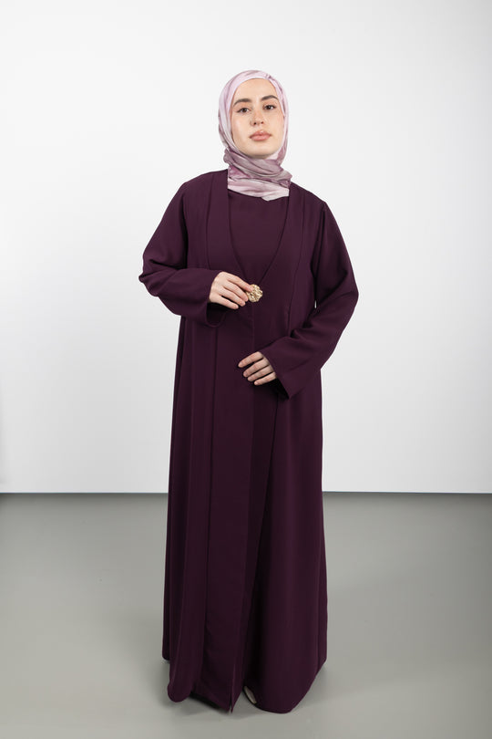 Woman wearing a long burgundy dress and hijab on a white background
