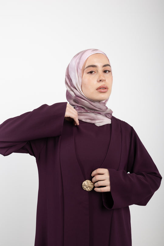 Woman wearing a purple outfit with a hijab on a white background