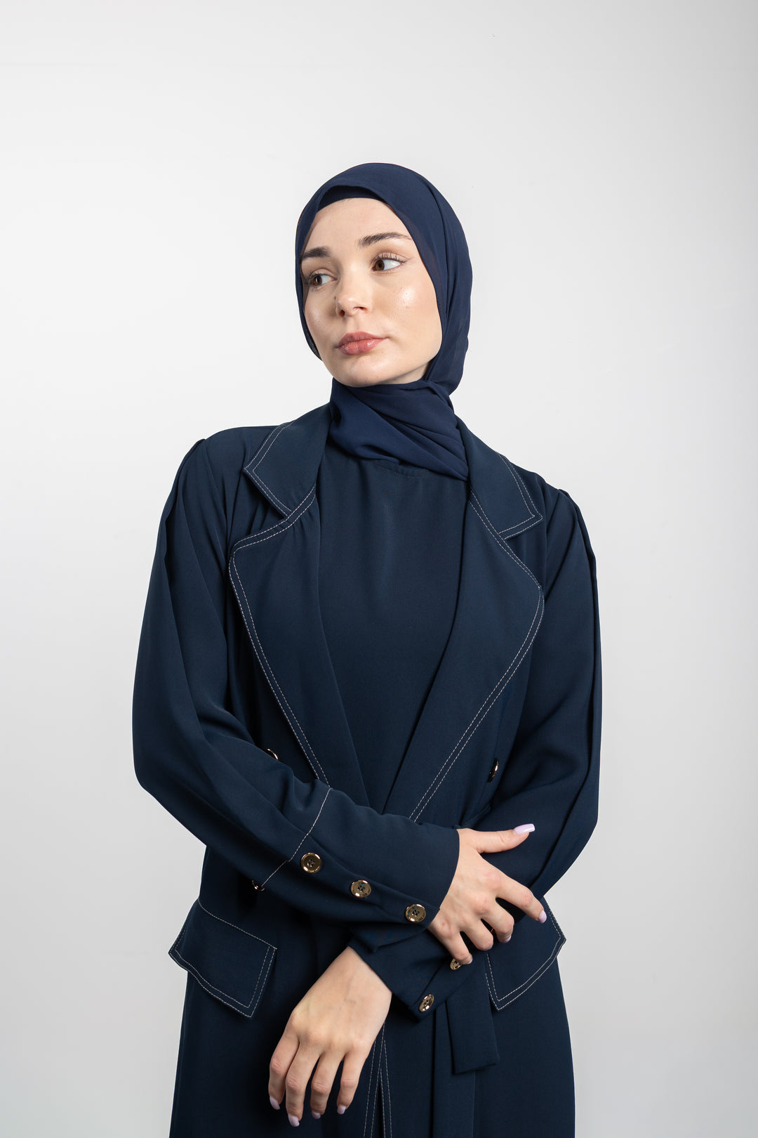 Woman wearing a navy blue outfit with a matching hijab on a white background