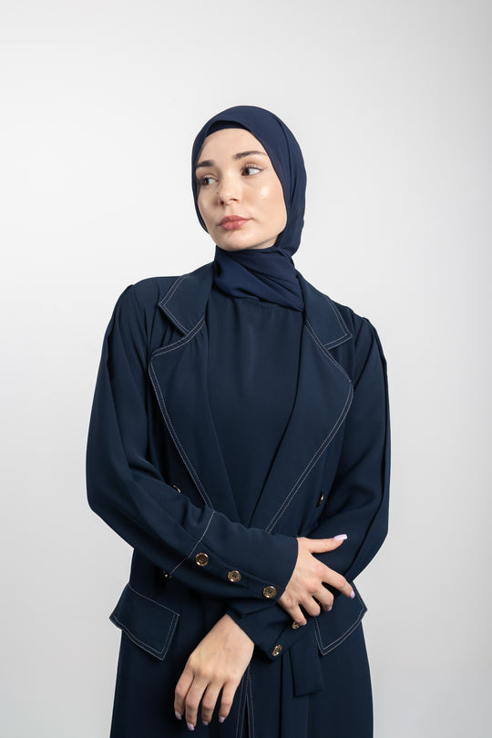 Woman wearing a navy blue outfit with a matching hijab on a white background