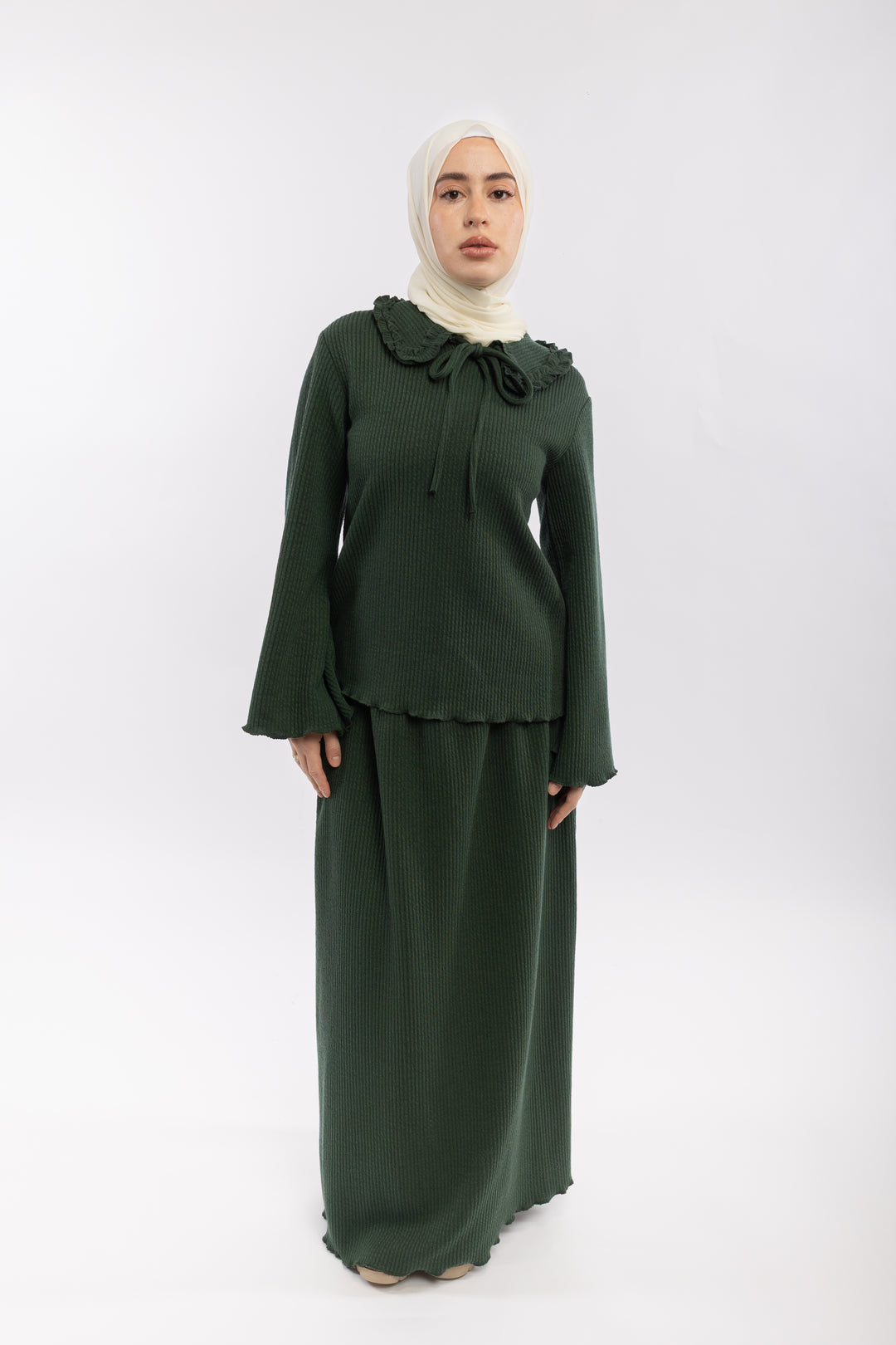 Woman wearing a green outfit with a white hijab on a white background
