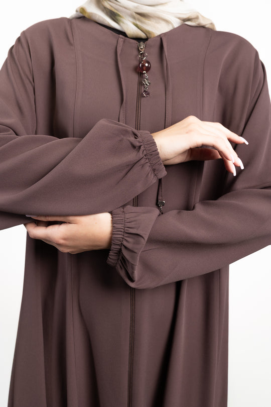 Brown long-sleeve garment with a close-up of the sleeve and hand on a white background