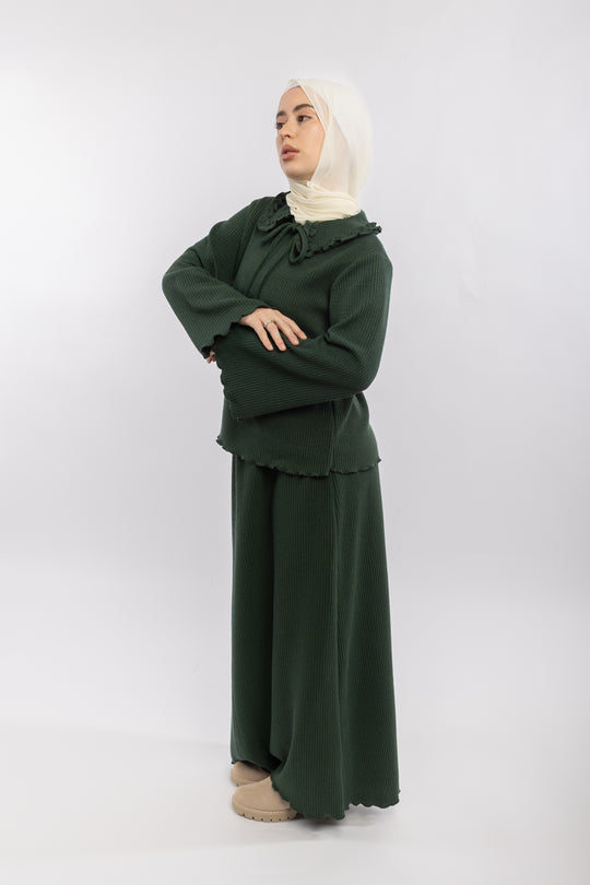 Woman wearing a green outfit with a beige hijab on a white background