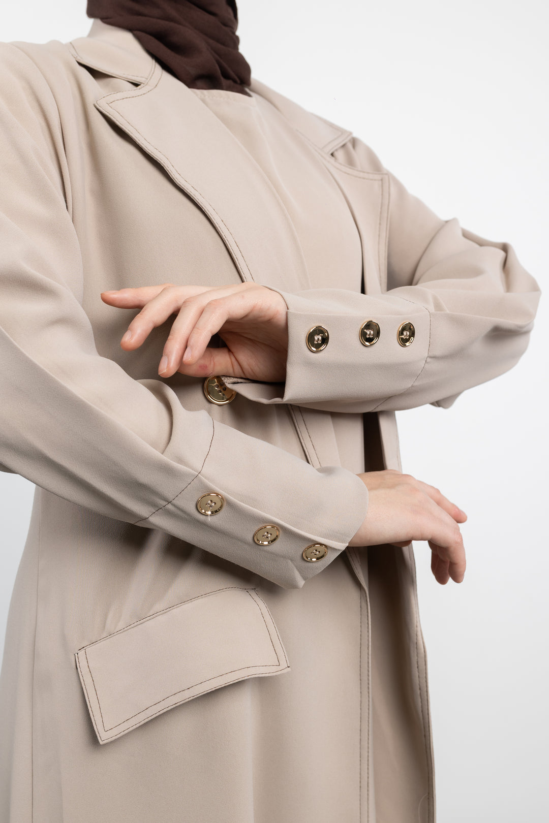 Beige trench coat Abaya with gold buttons on a white background