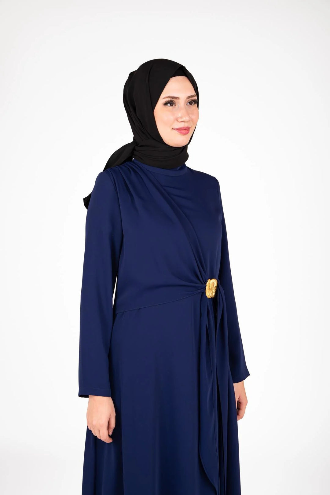 Woman wearing a navy blue dress with a black hijab on a white background