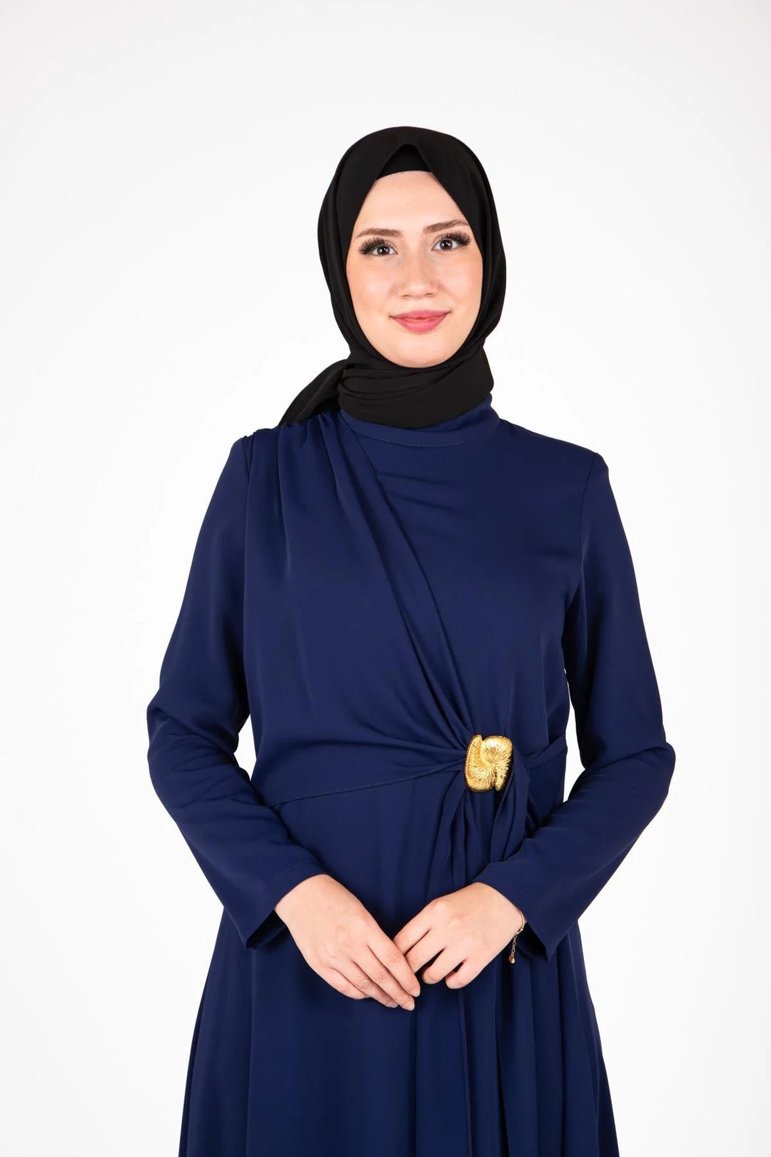 Woman wearing a navy blue dress with a black hijab on a white background