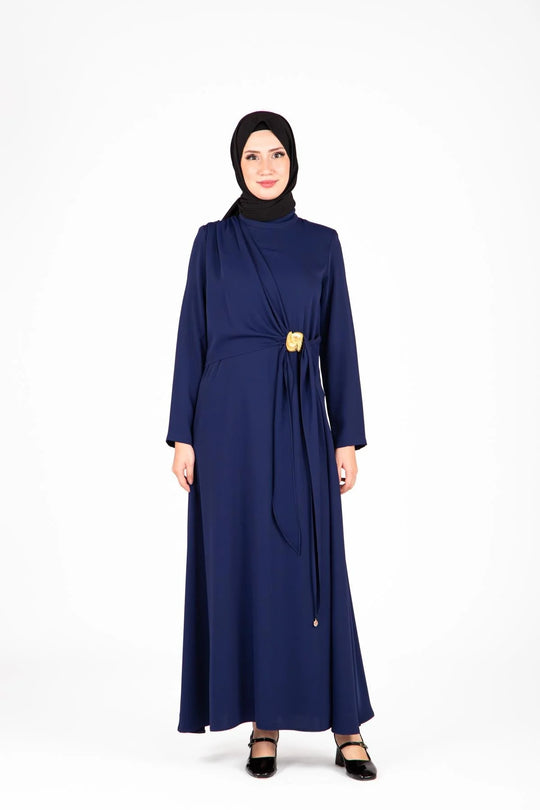 Woman wearing a navy blue dress with a black hijab on a white background
