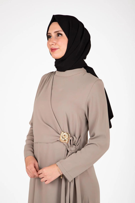 Woman wearing a beige dress with a black hijab on a white background