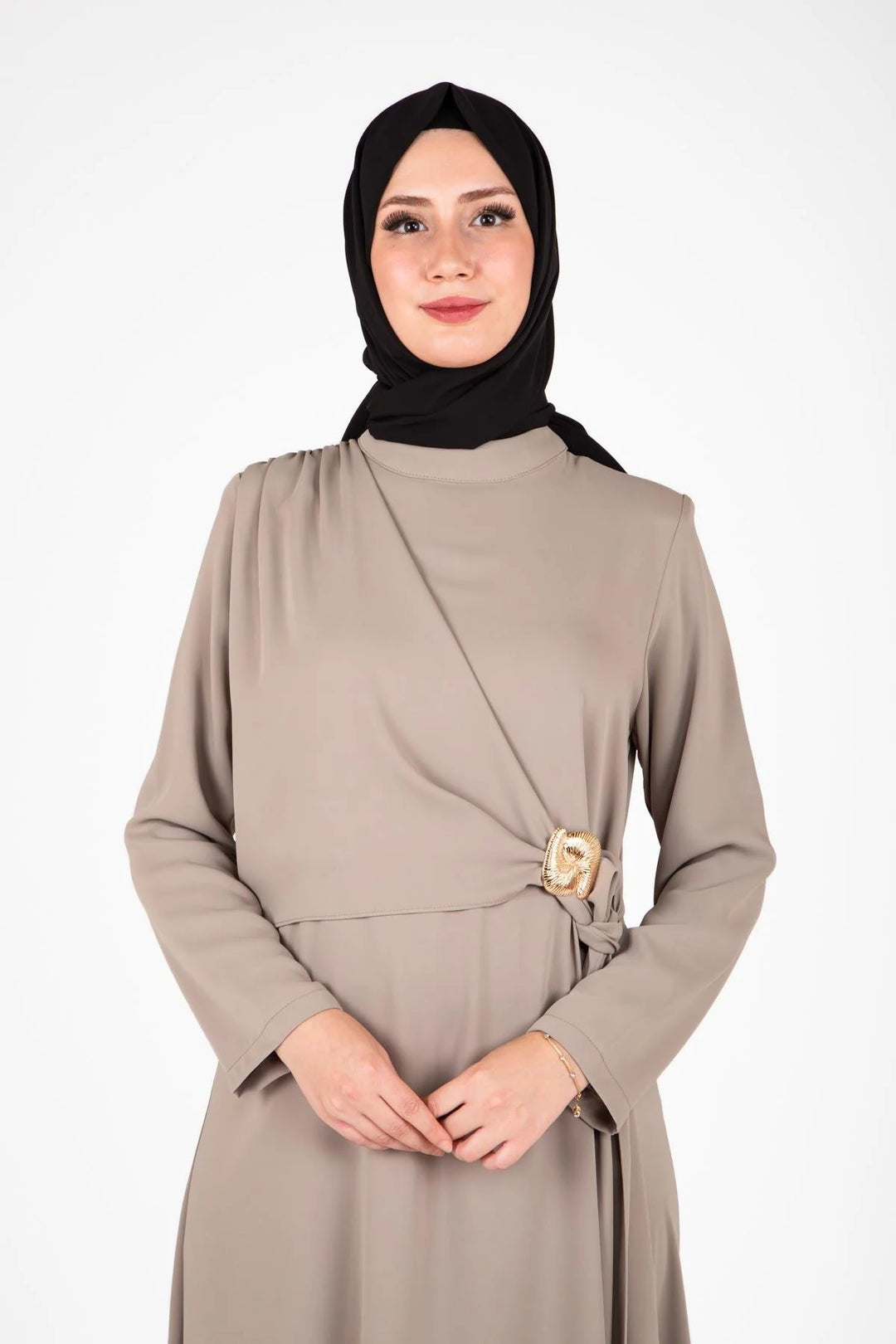 Woman wearing a beige dress with a black hijab on a white background