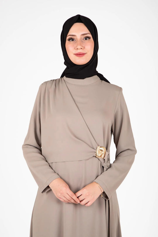 Woman wearing a beige dress with a black hijab on a white background