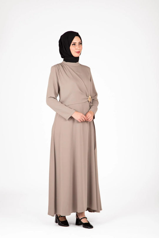 Woman wearing a beige dress with a black hijab on a white background
