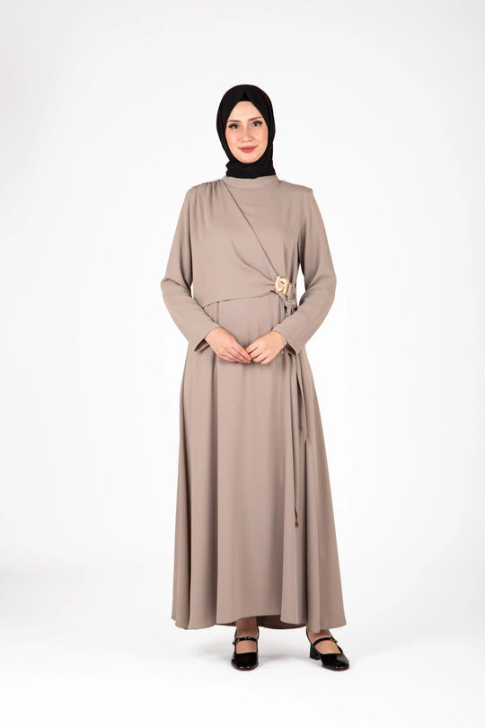 Woman wearing a beige dress with a belt on a white background